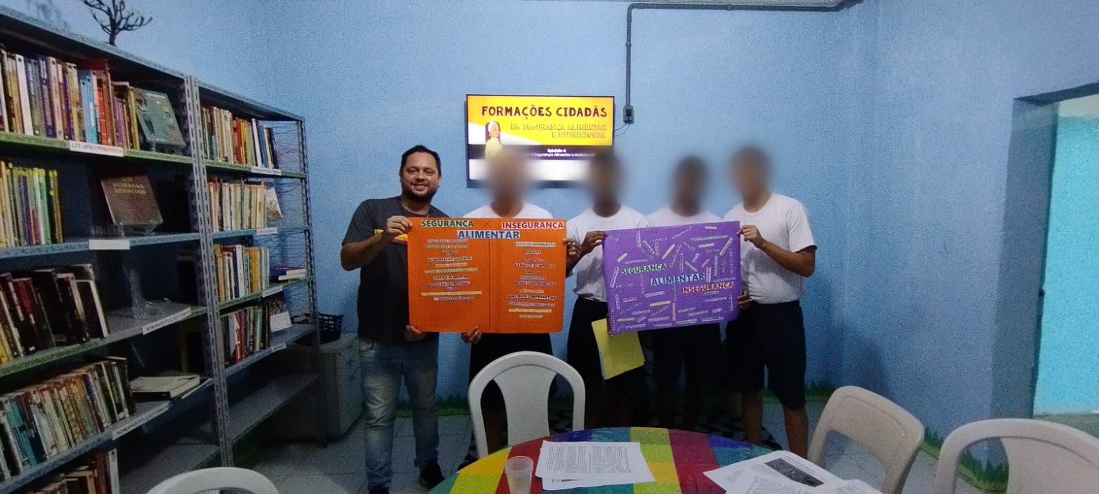 Jovens na Biblioteca do Cense, segurando cartaz 
