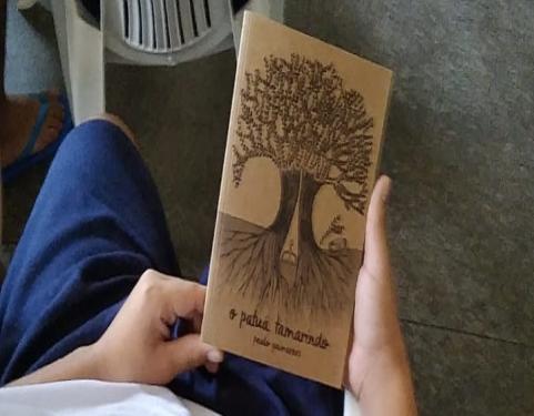 Adolescente segurando o livro "Patuá Tamarindo"