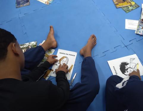 Socioeducando faz uma colagem com o rosto de Maria da Penha 