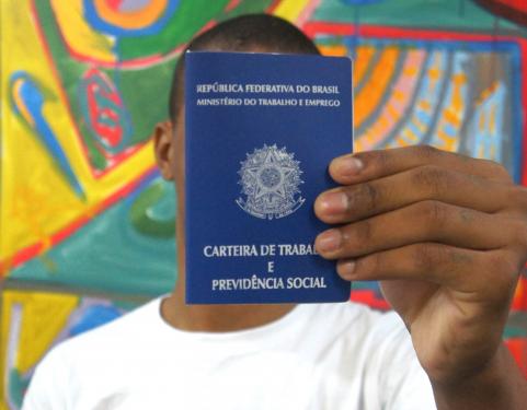 Jovem segura CTPS em primeiro plano 