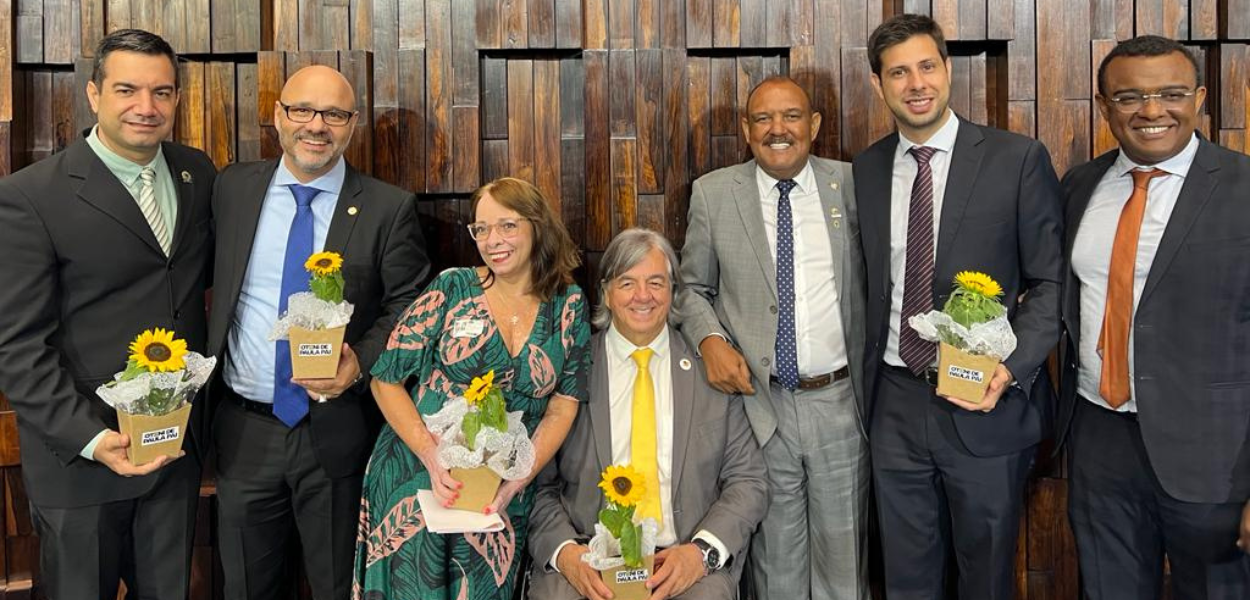 Participantes da homenagem segurando girassóis