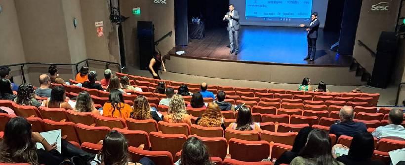 auditório com dezenas de pessoas sentadas 