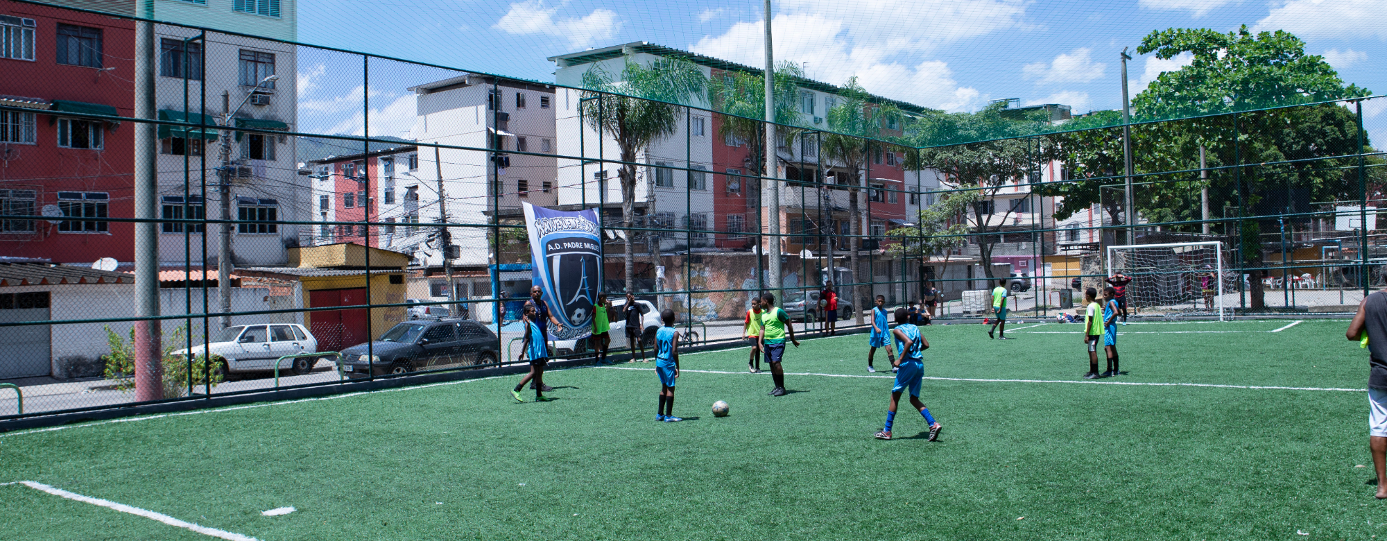 Na imagem contém crianças jogando futebol no campo de futebol inaugurado