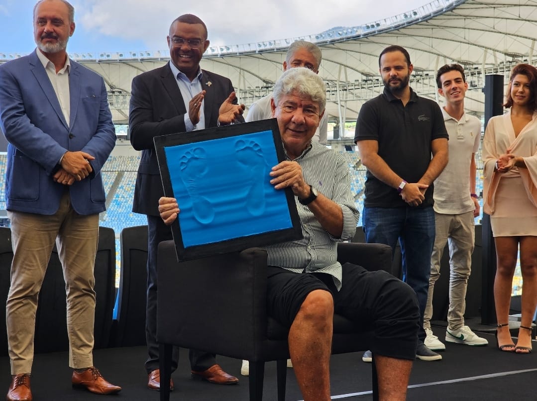 Um homem sentando, segurando uma placa com a marca de seus pés.